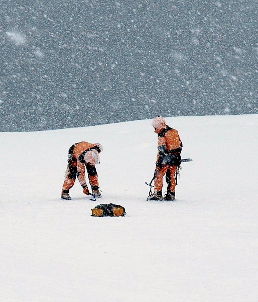 Six people in snowy weather adjusting ropes and rescue equipment.