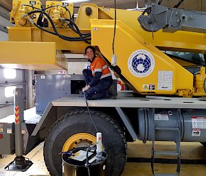 Expeditioner kneels on heavy machinery performing checks