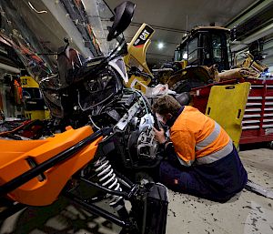 An expeditioner in hi-vis works on a vehicle in a workshop.