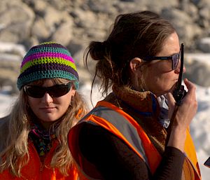 Two women in Antarctica. One using a radio.