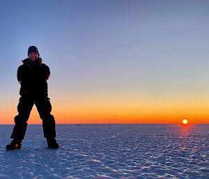 Station leader standing on the ice with the sunrise behind