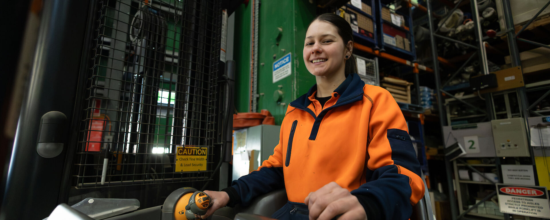A woman in hi vis orange on a forklift