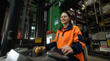 A woman in hi vis orange on a forklift