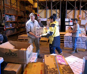 Two people carrying a box in the warehouse.