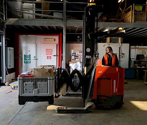 An expeditioner drives a forklift in a warehouse.