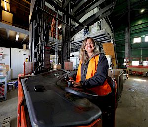 An expeditioner drives a forklift in a warehouse.