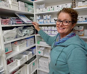 Doctor standing next to well stocked shelves of medical supplies.