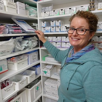 Woman in dispensary taking a dressing off shelf.