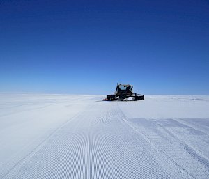 Snow groomer working on runway.