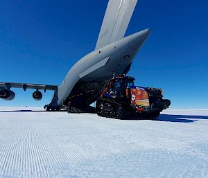 A tractor on the ice next to a large aircraft.