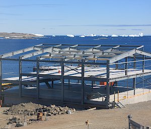 Partially constructed building with ocean and icebergs in background.