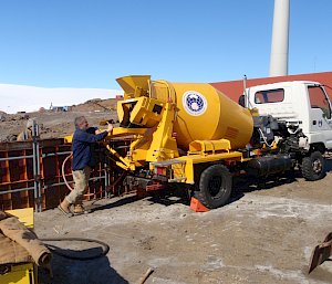 Man adjusting concrete mixing truck.