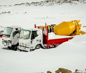 Two concrete mixer trucks half buried in snow.