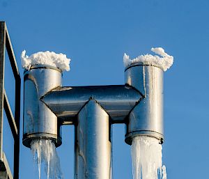 Rooftop vent freezes over with ice and icicles attached at all sides.