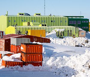 Colourful containerised buildings with large piles of snow surrounding them.