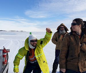 Three expeditioners laughing with one fist pumping at the ice runway