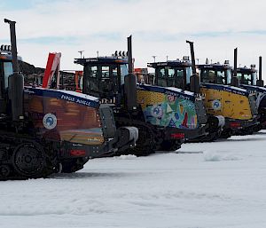 A row of tractors with brightly coloured artworks printed on them.
