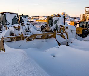 Heavy machinery covered with snowdrifts.