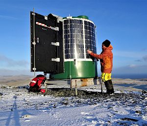 Expeditioner checking solar panels on a small round metal structure.