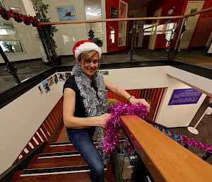 An expeditioner puts tinsel on a stair banister.