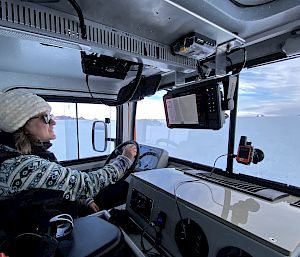 Expeditioner inside a left-hand drive vehicle, with Antarctic landscape through the windows