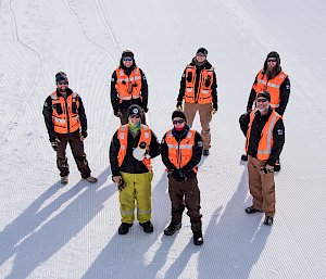 Group of expeditioners in high visibility vests standing on ice.