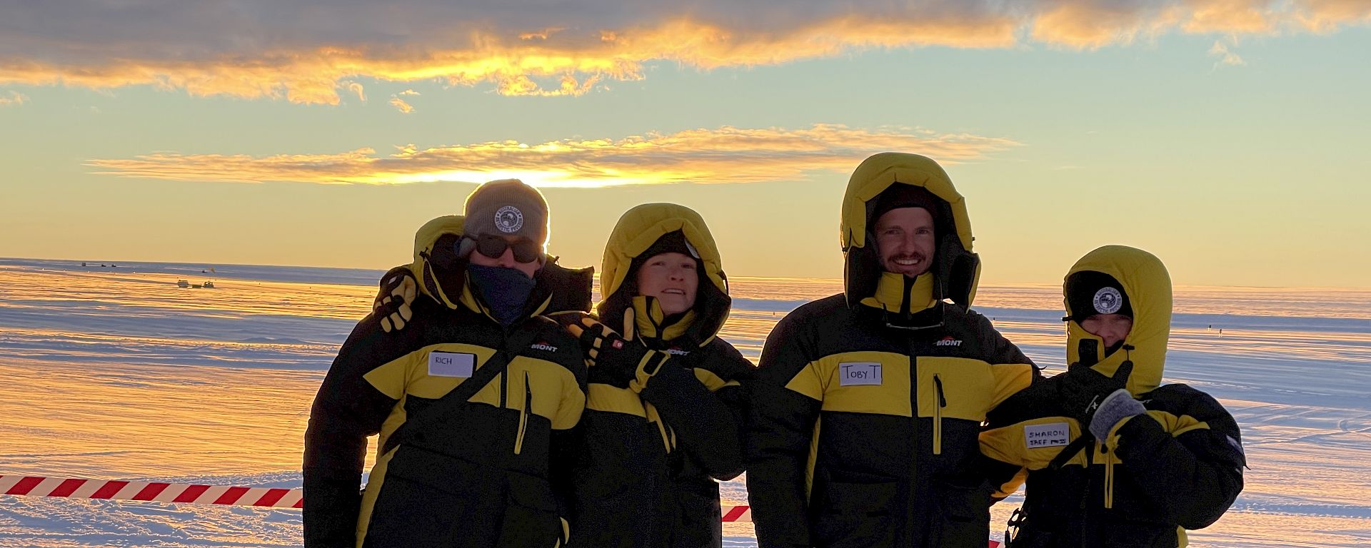 4 expeditioners stand together on the ice.
