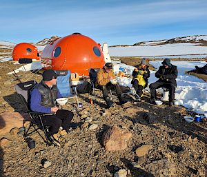 Tents and hard-shell tents in a cluster in a remote icy landscape