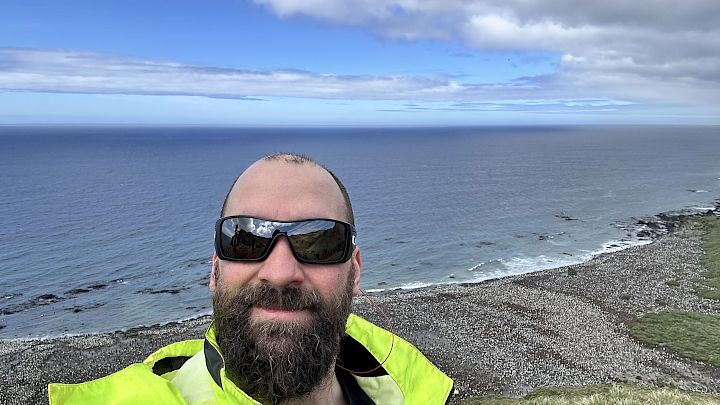 Selfie image of Cris with the shore and ocean in the background