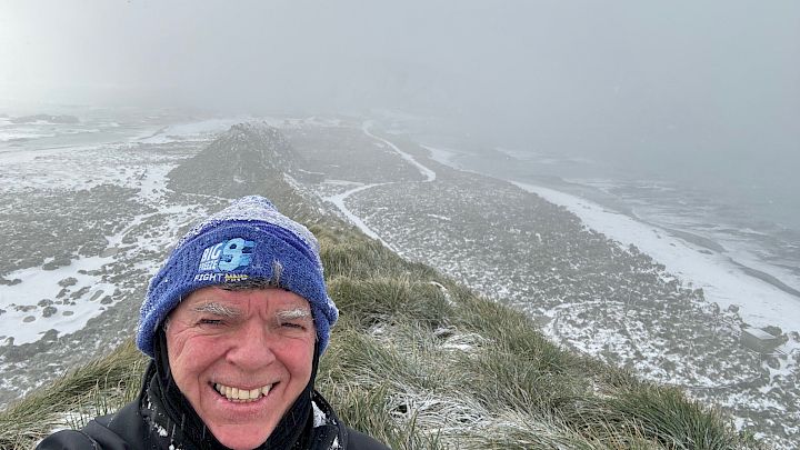 Expeditioner with snowy tussocks and misty background behind