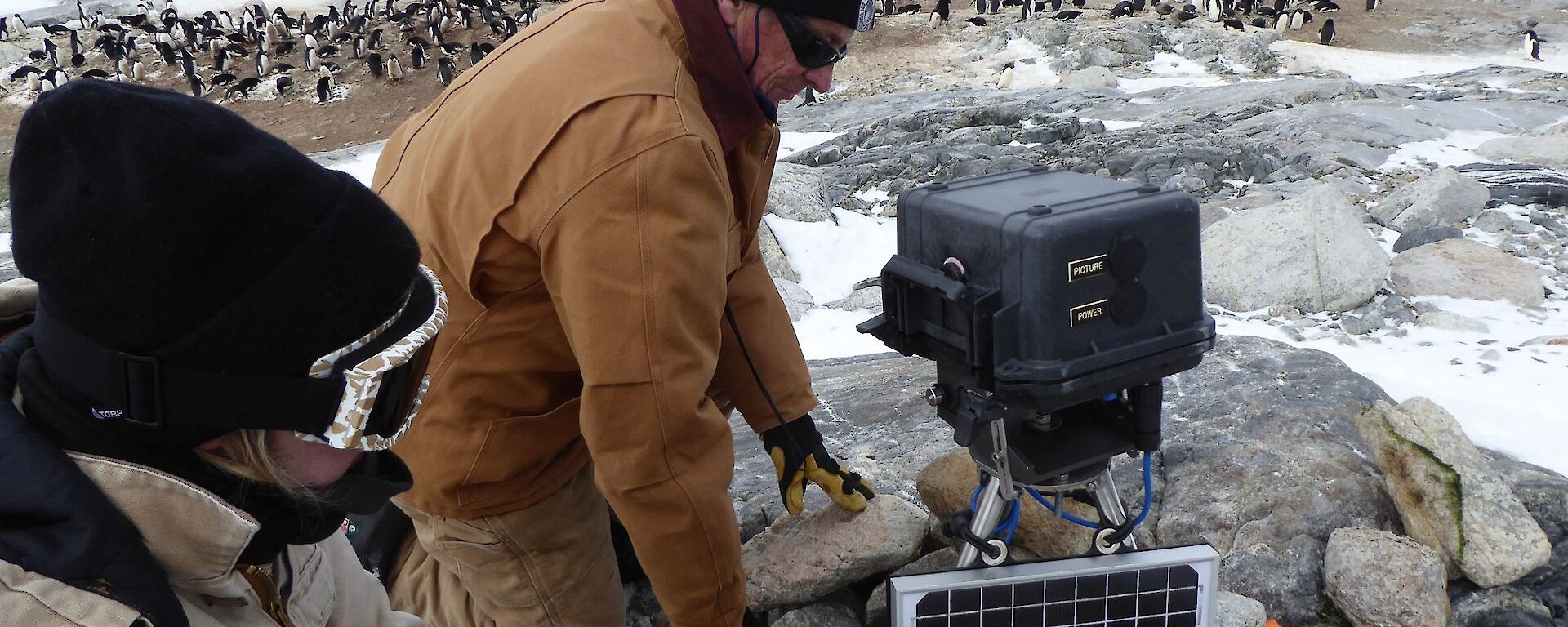Two researchers setting up a new camera to monitor the Adelie penguin colony