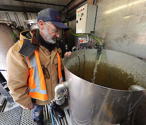 An expeditioner stands in a container next to a large drum.