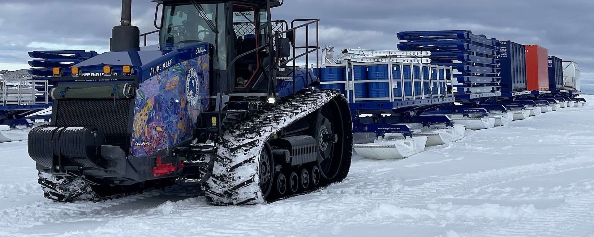 An expeditioner stands next to a long ice core on a table in an icy landscape.