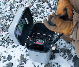 Close up of an expeditioner's hands using the high-frequency radio in the field