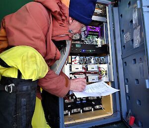 Expeditioner with clipboard checking the repeater hut equipment