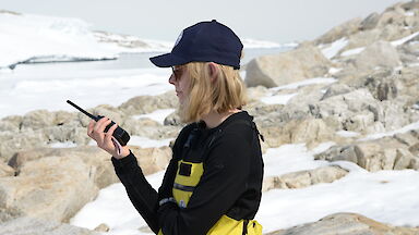 An expeditioner holds a walkie-talkie.