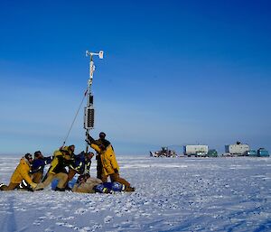 Group of expeditioners near mast with tractor train in background